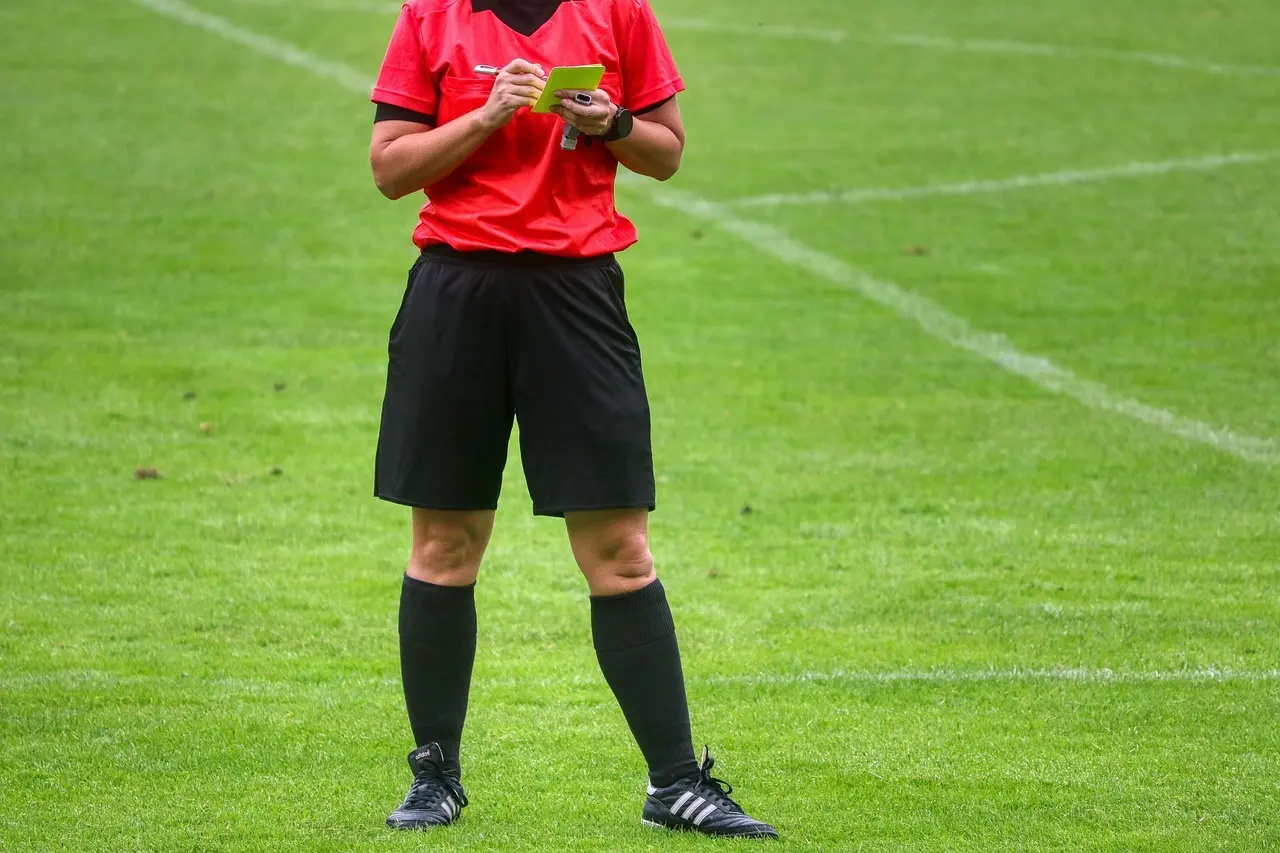 Fodbolddommer på en græsbane noterer i en notesblok